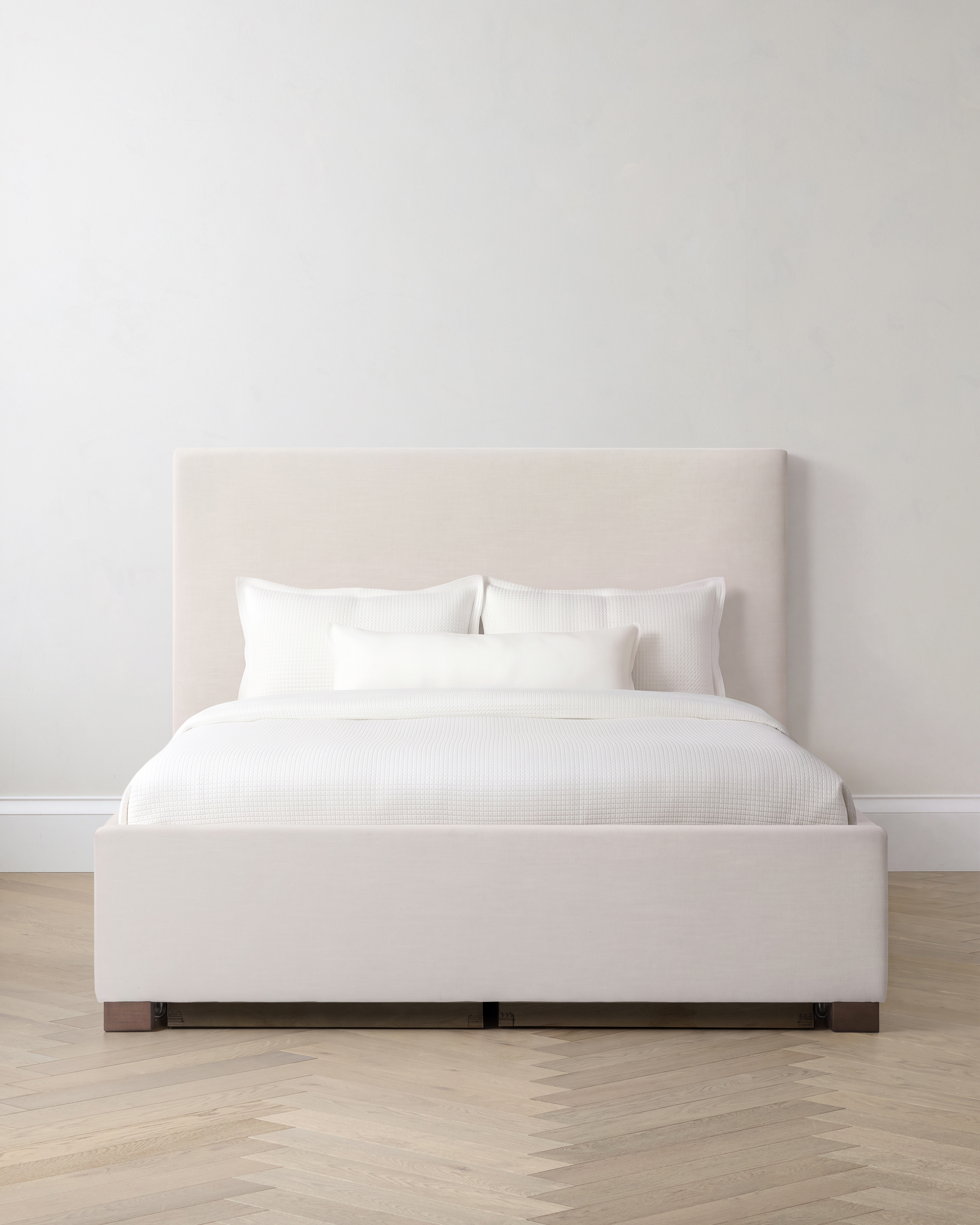 White storage bed with white linens and headboard on a light room.