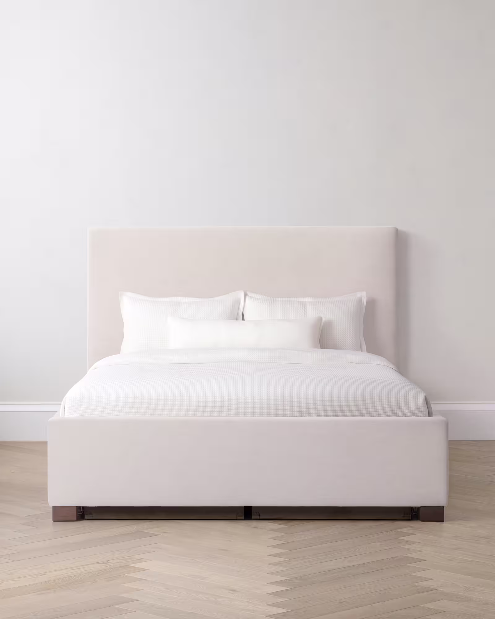 White storage bed with white linens and headboard on a light room.