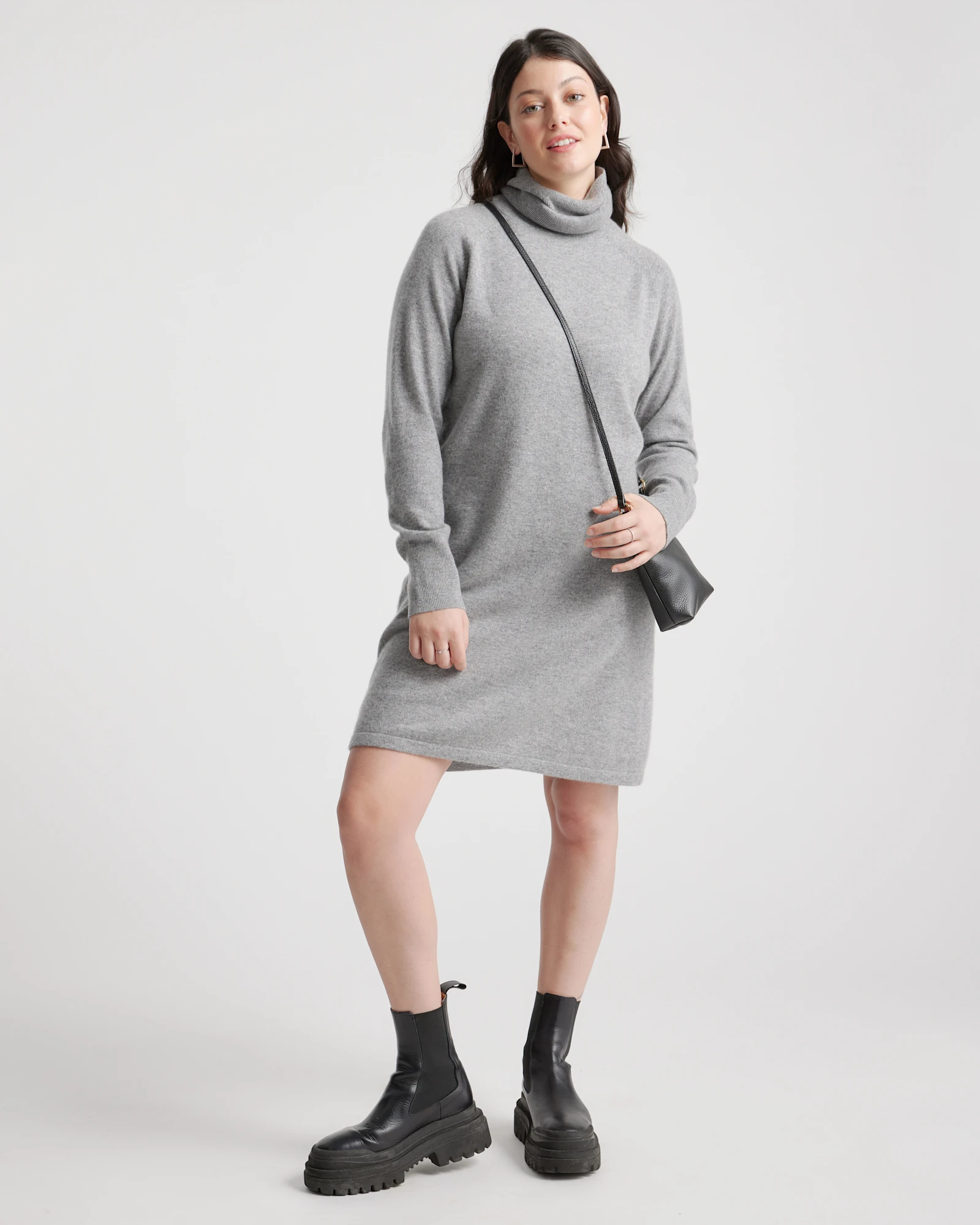 Grey turtleneck sweater dress with long sleeves, worn with chunky black boots and a small crossbody bag