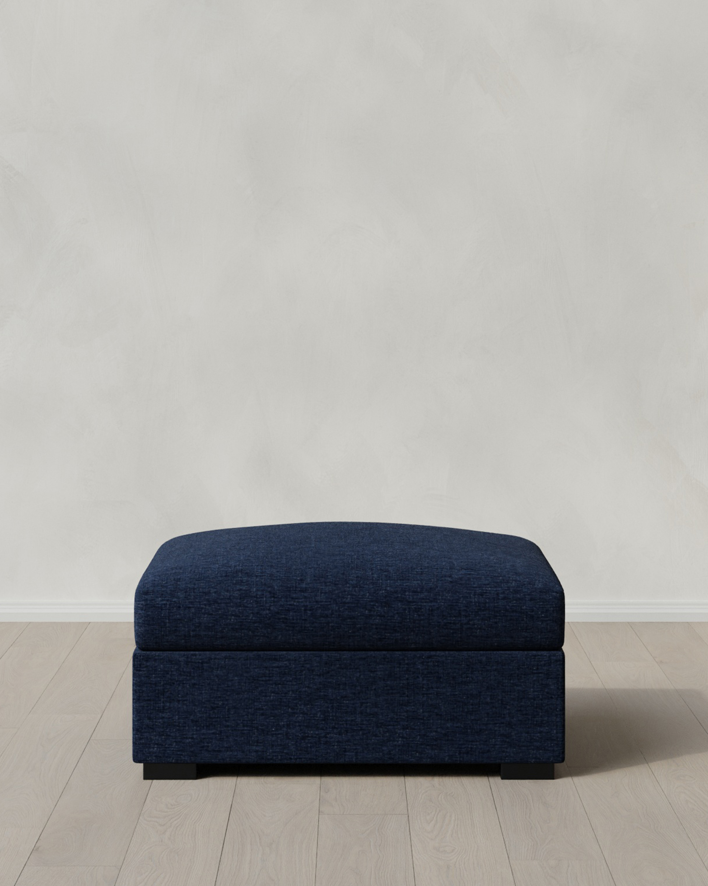 Dark blue ottoman on a light wooden floor.